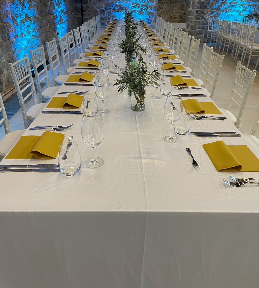 A banquet table set for dinner in a stone hall at an event organised by Adria Congress